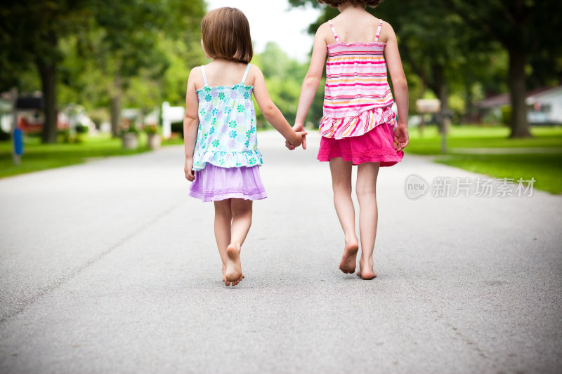 两个快乐的姐妹手牵着手走在外面