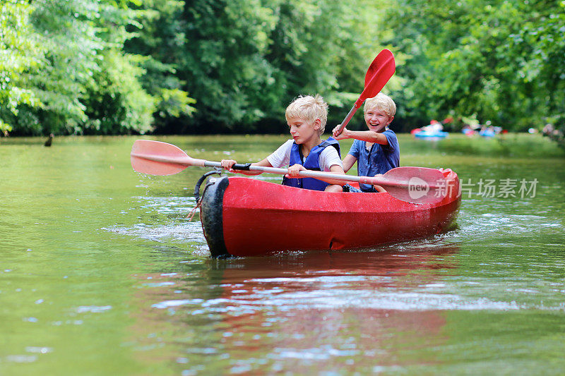 两个快乐的男孩在河上划独木舟