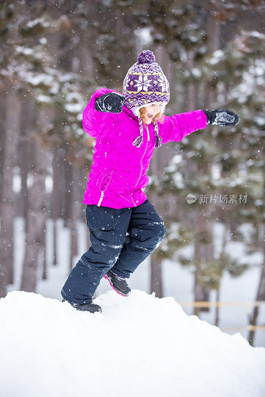 年轻女孩在冬天从雪堆上跳下来