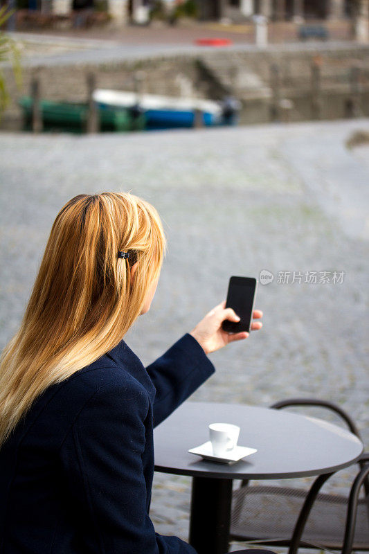 年轻女子在咖啡馆用手机发短信秋天