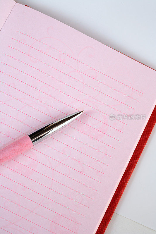 粉红色和红色笔记本与钢笔