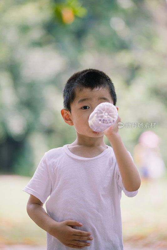 亚洲男孩用塑料瓶喝酒