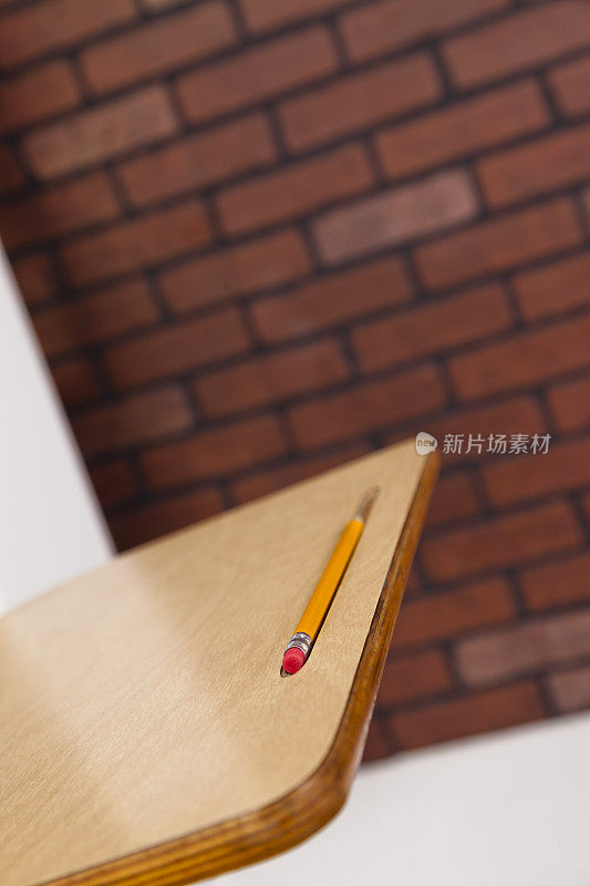 在以砖为背景的教室里，铅笔放在学生的课桌上