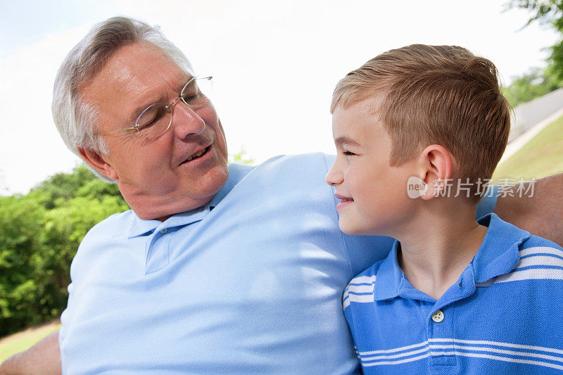 孙子和爷爷在公园长椅上互相看着