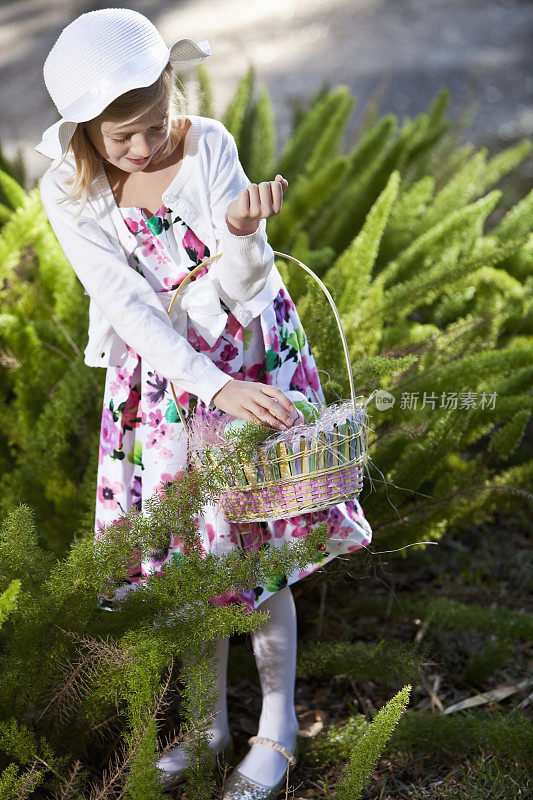 小女孩把复活节彩蛋放在篮子里