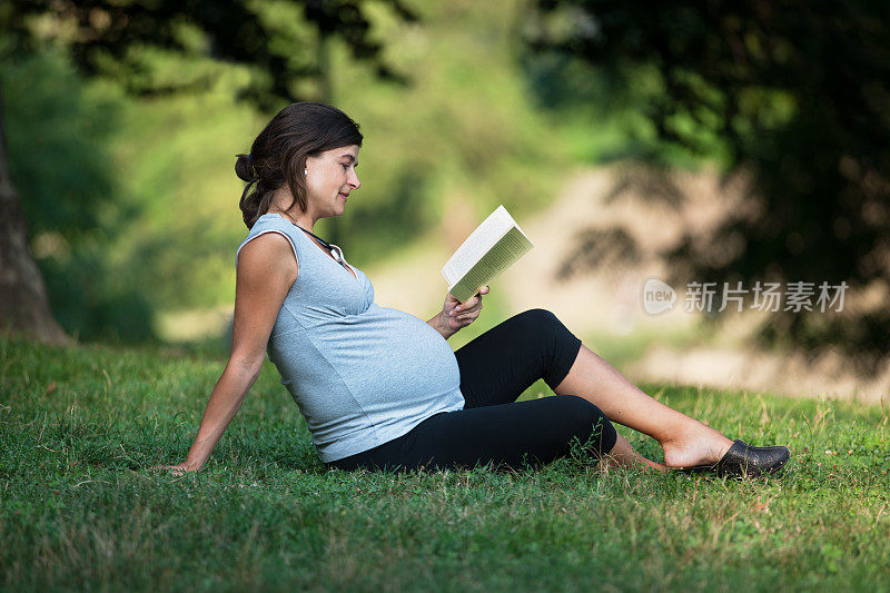 一个孕妇坐在草地上看书