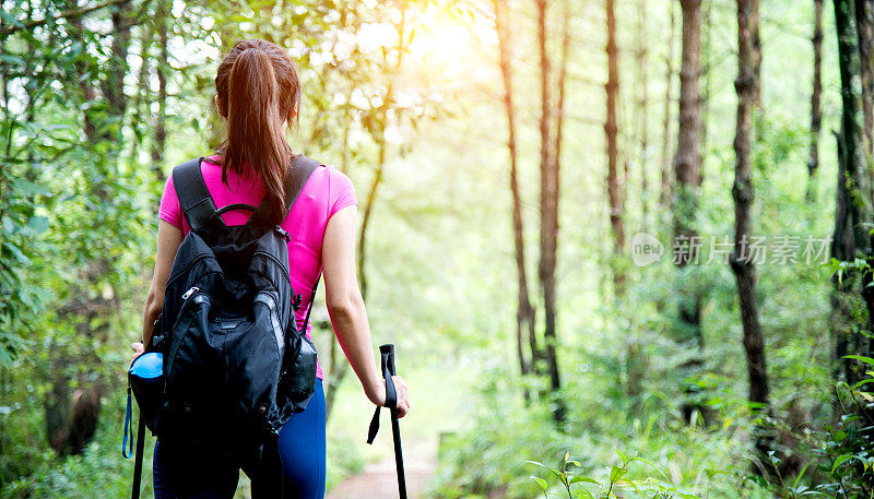 在树林里背着背包的年轻女性徒步旅行者