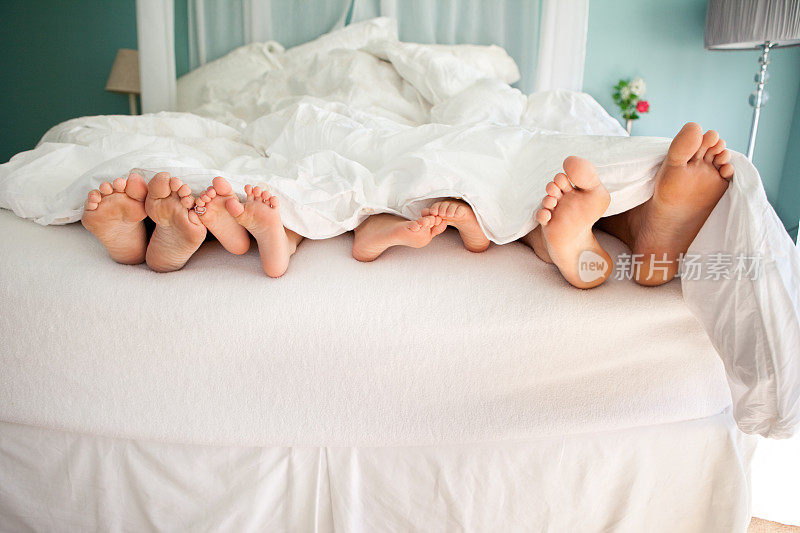 年轻的家庭在床上赤着脚