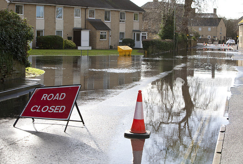 被水淹没的住宅道路上的警告标志和柱子