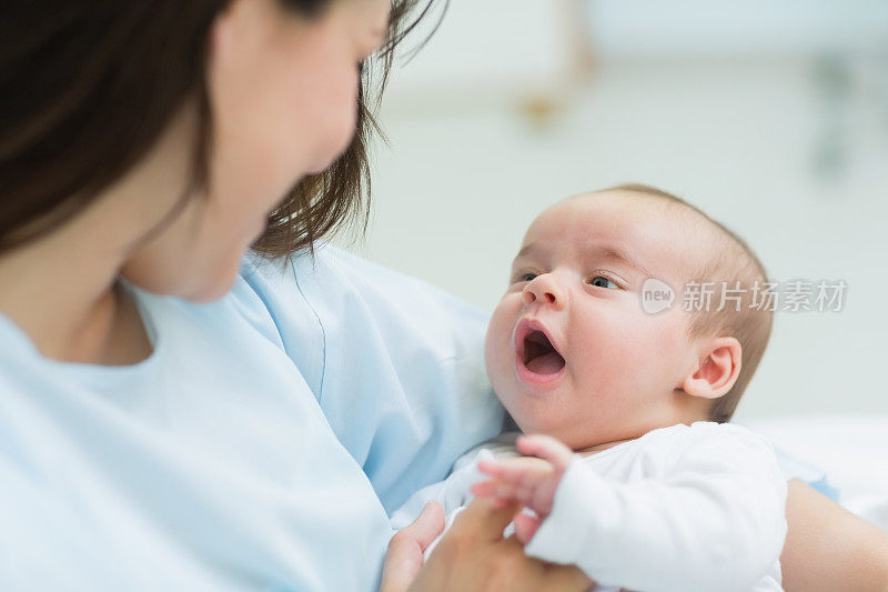 妈妈抱着一个婴儿，他正在张嘴