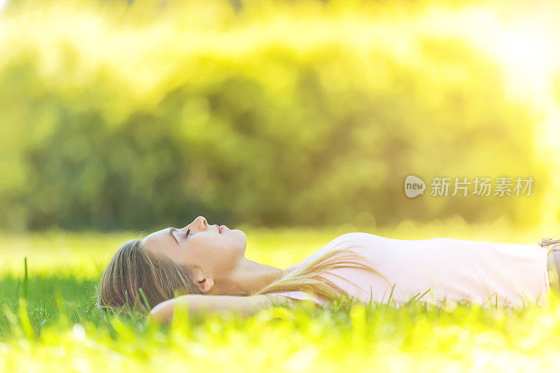 一个美丽的女人在公园的草地上休息