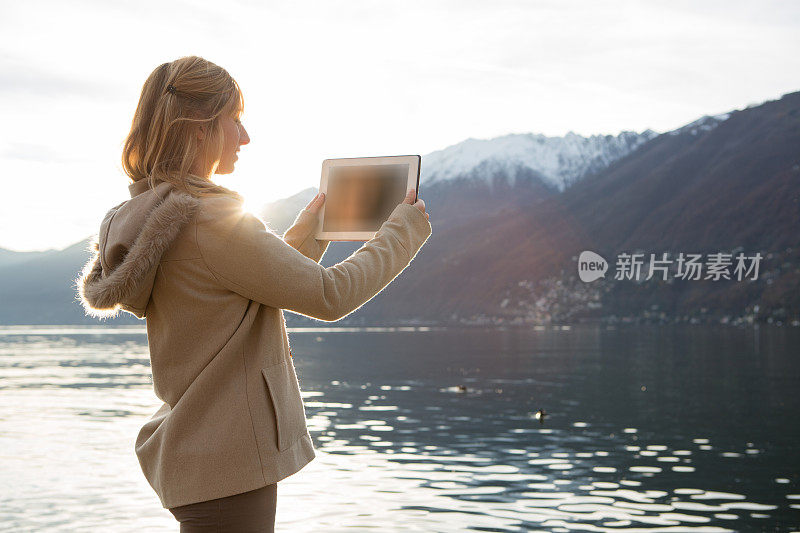 一名女子在湖边用数码平板电脑秋拍照