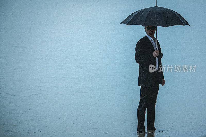 一个穿西装撑伞的帅哥站在水里
