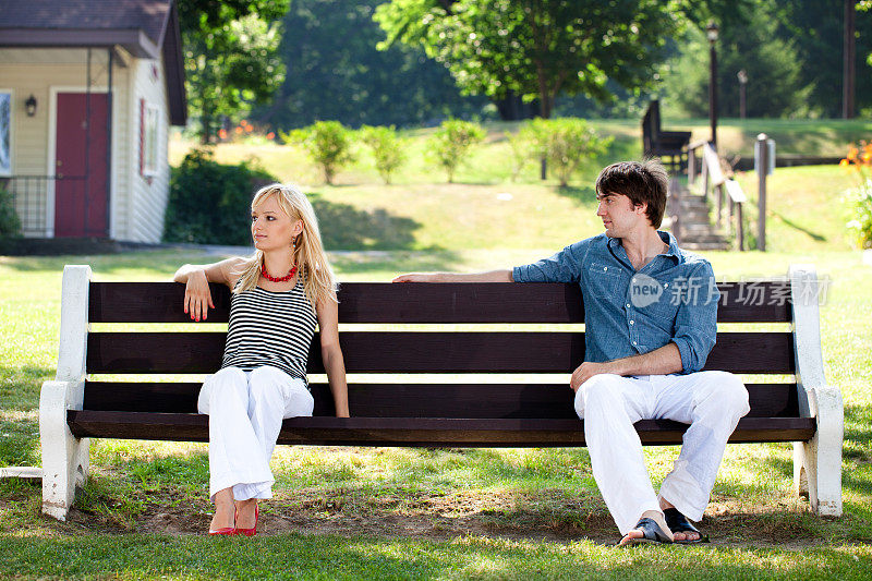 一个年轻女人无视一个坐在户外长椅上的男人