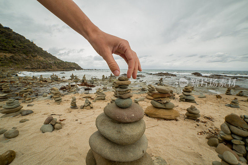 人们在海边的卵石塔上堆起最后一块石头