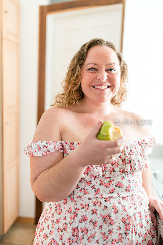 胖女人在厨房里吃苹果