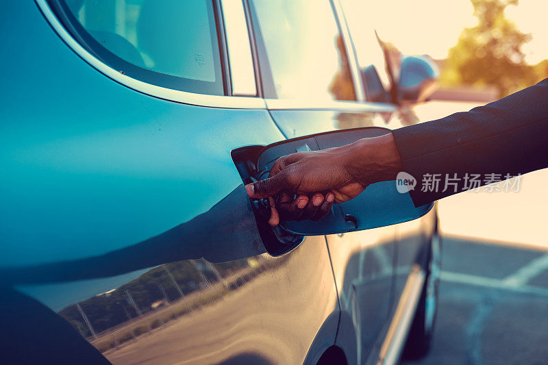 一个黑人的手臂靠近汽车的油箱。