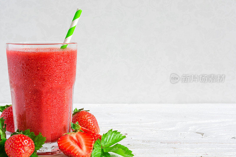 草莓冰沙在一个玻璃杯，吸管和新鲜浆果