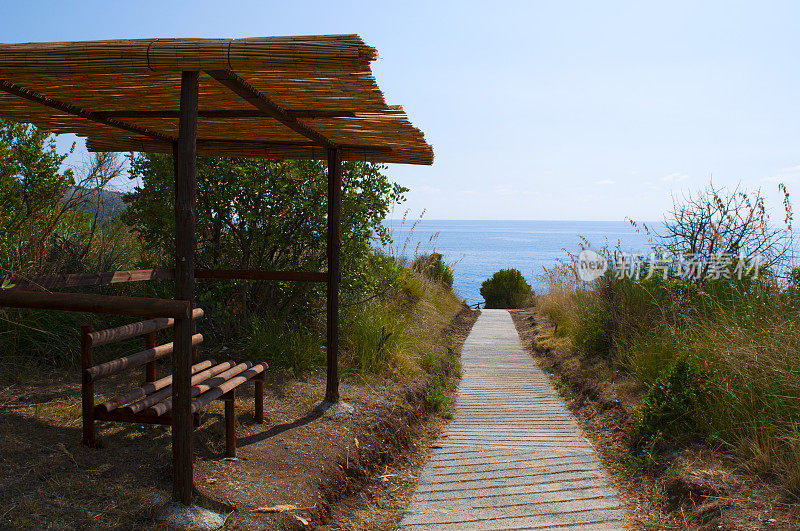 卡拉布里亚:通向阿科马格诺海滩的小路上的一条长椅，大拱门海滩，一个隐藏的小海湾，在几个世纪的海浪中形成了一个天然的拱门