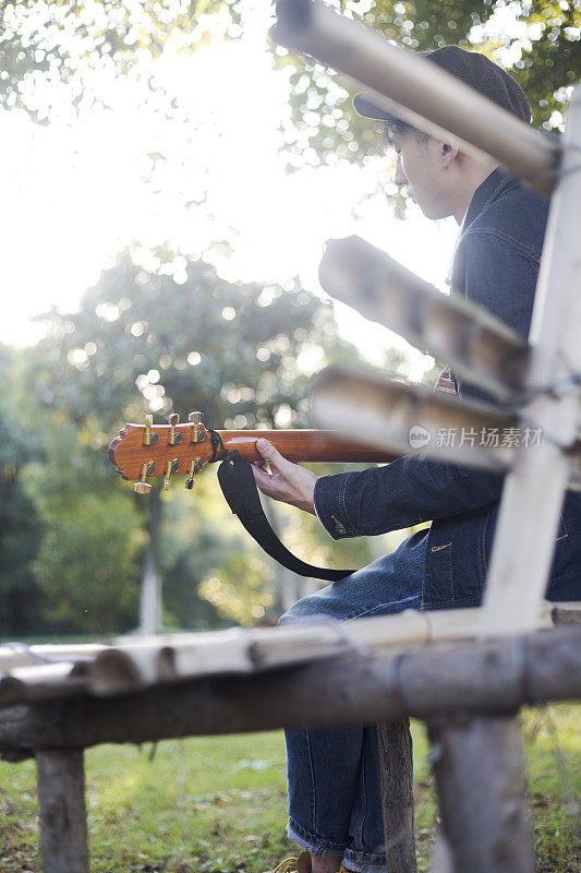 一个年轻人在公园的长椅上弹吉他