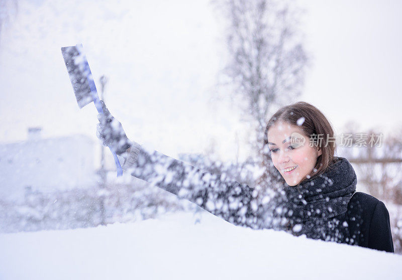 冬天即将来临。女人在冰冷的天气里，车被雪覆盖着。