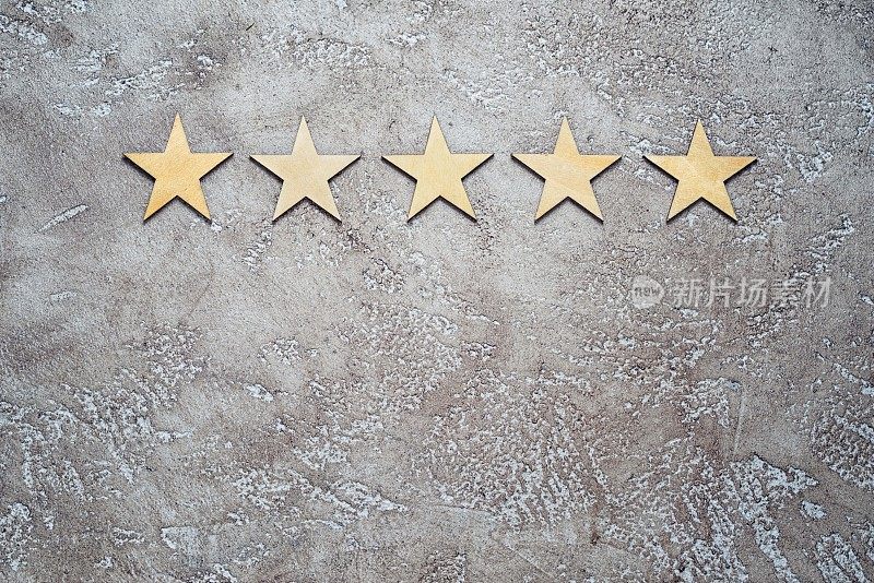 五颗木质星星排列在中性米色纹理水泥背景上，顶部视图与复制空间。最佳评价客户反馈概念。
