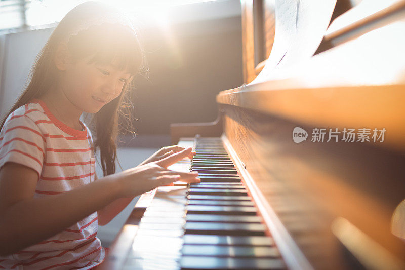 微笑的女孩在教室里练习钢琴