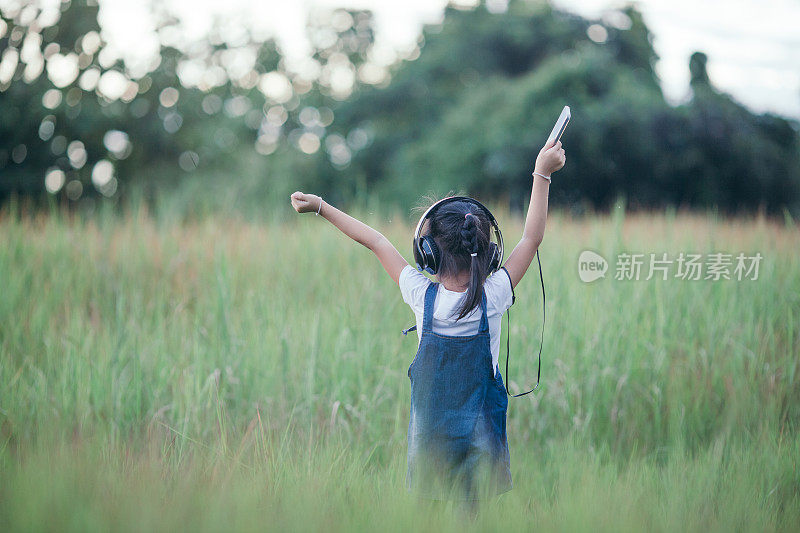 儿童，科技和休闲概念-女孩与耳机躺在自然和听音乐