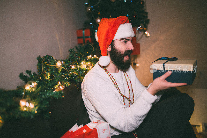 戴着圣诞帽的大胡子男人打开圣诞礼物