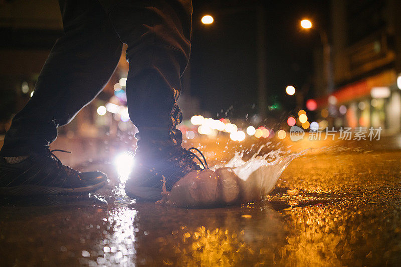 一个不认识的人在雨夜踏进水坑