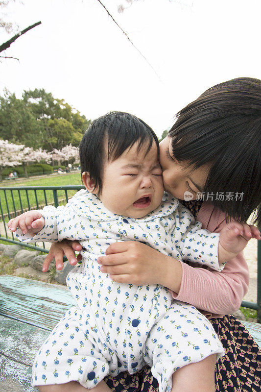 姐姐抱着哭闹的婴儿在外面