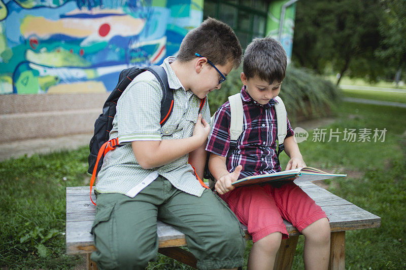 男孩坐在学校操场的长椅上，放学后