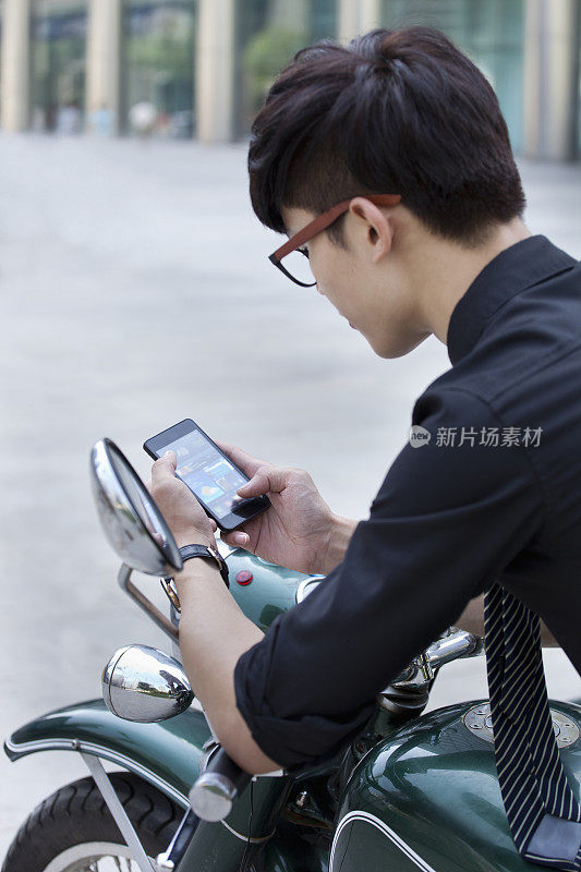 中国商人在摩托车上使用手机
