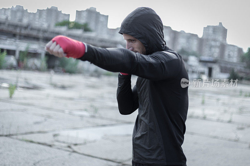 在一个寒冷的日子里，一个穿黑衣服的壮汉正在废弃的工厂里打拳击