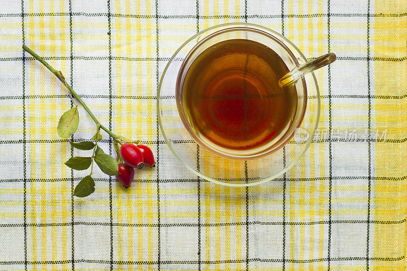 一杯茶和玫瑰果和叶子的格子布