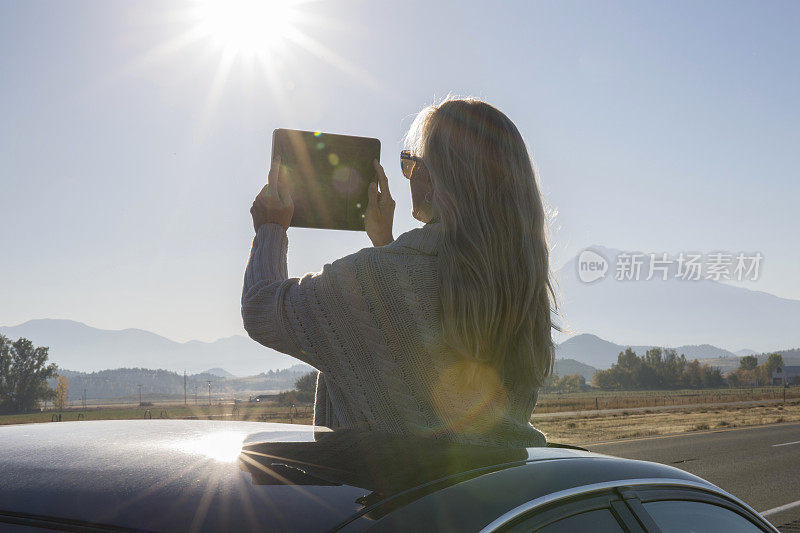 女人站在车里，在路上拍照