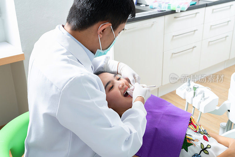 牙科医生在牙科诊所的牙医椅上检查病人的牙齿。牙科医生在他的诊所里治疗病人的牙齿。