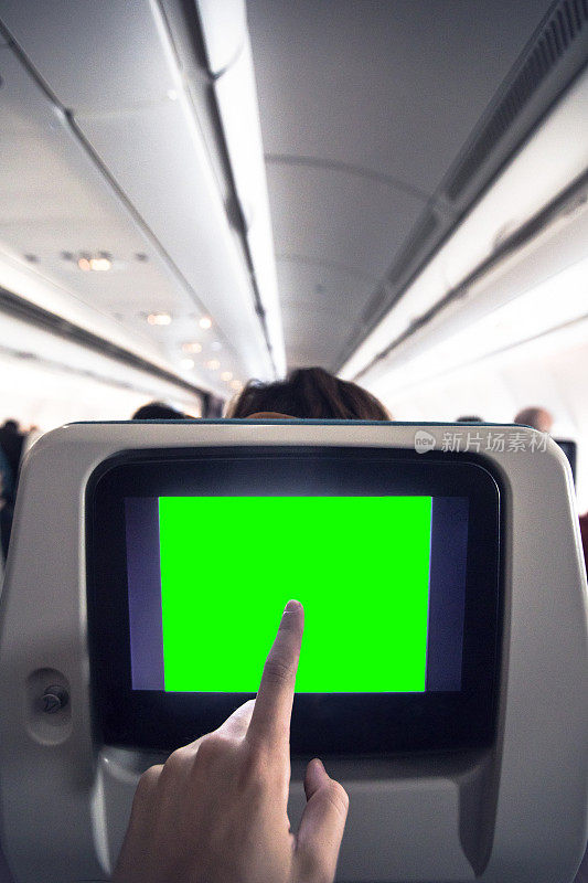 年轻男子在点击飞机座椅数字平板电脑的绿屏
