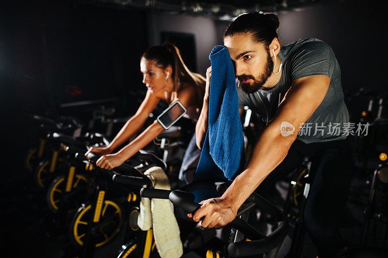 两个年轻人在健身房骑着健身车锻炼