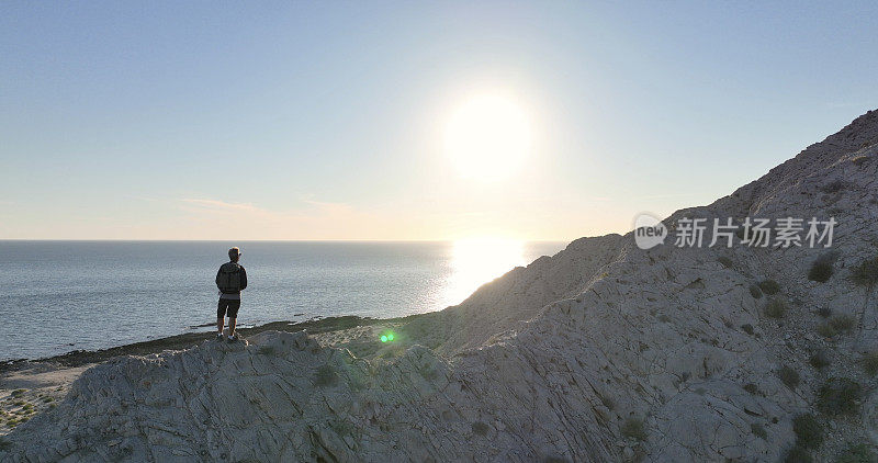 鸟瞰图，徒步旅行者在阳光明媚的海岸悬崖上放松