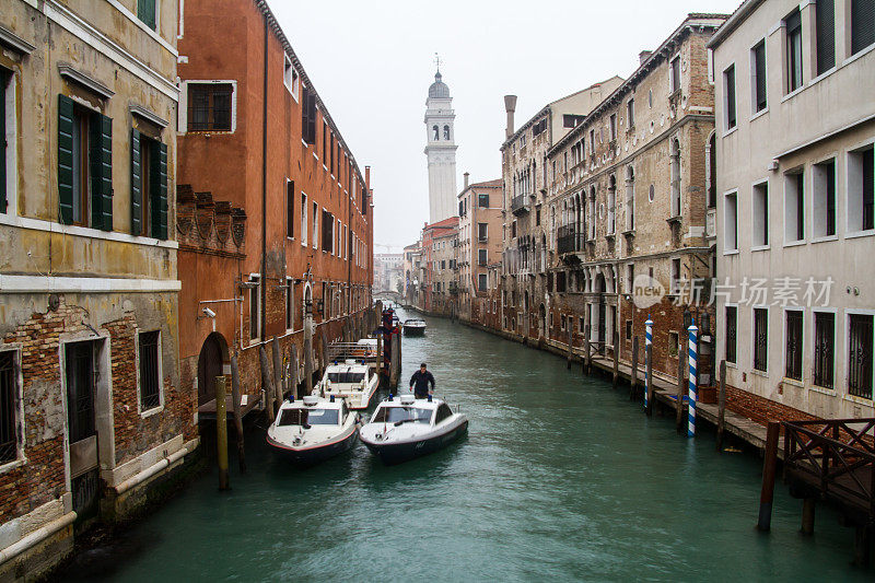 日常生活在威尼斯的船都在运河上，天气都在下雨的水平照片