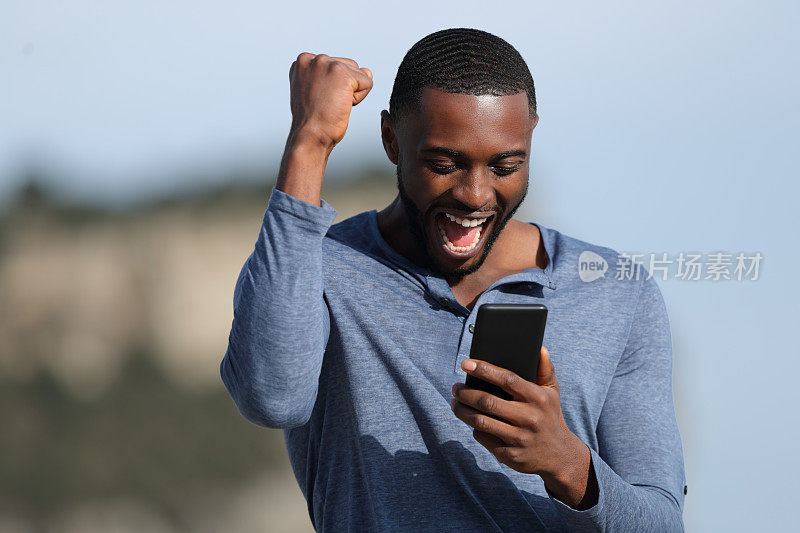 一个黑皮肤的男人在庆祝看手机