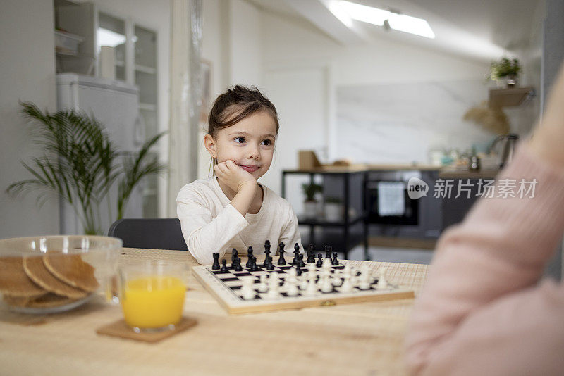 一个白人小女孩和她奶奶在家里下棋