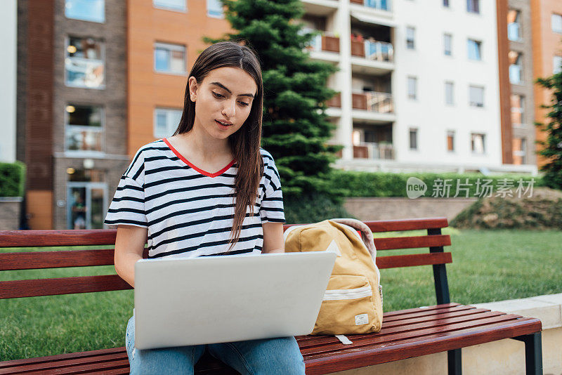 一个女孩用笔记本电脑在户外学习的肖像