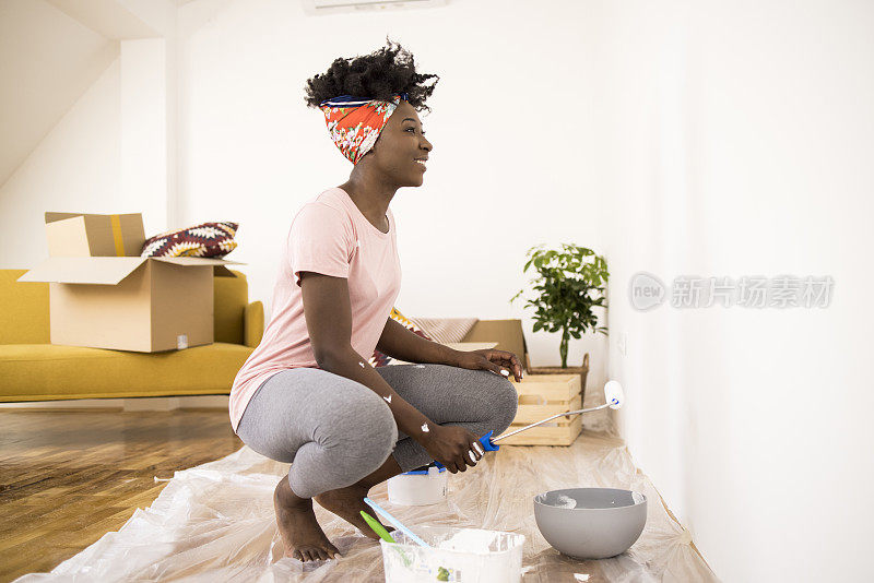 快乐的非洲妇女在家里画墙，享受