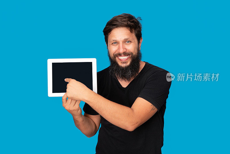 微笑的男人的肖像，拿着数码平板电脑的蓝色背景