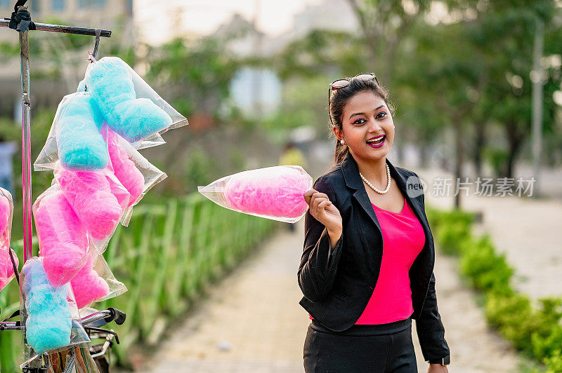 可爱的女人吃棉花糖在游乐场