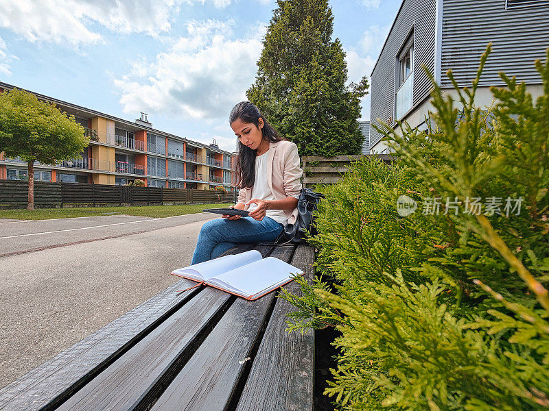 年轻的印度女商人在户外用数字平板电脑工作