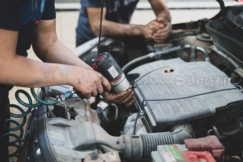 汽车修理工在汽车修理厂修理汽车发动机。