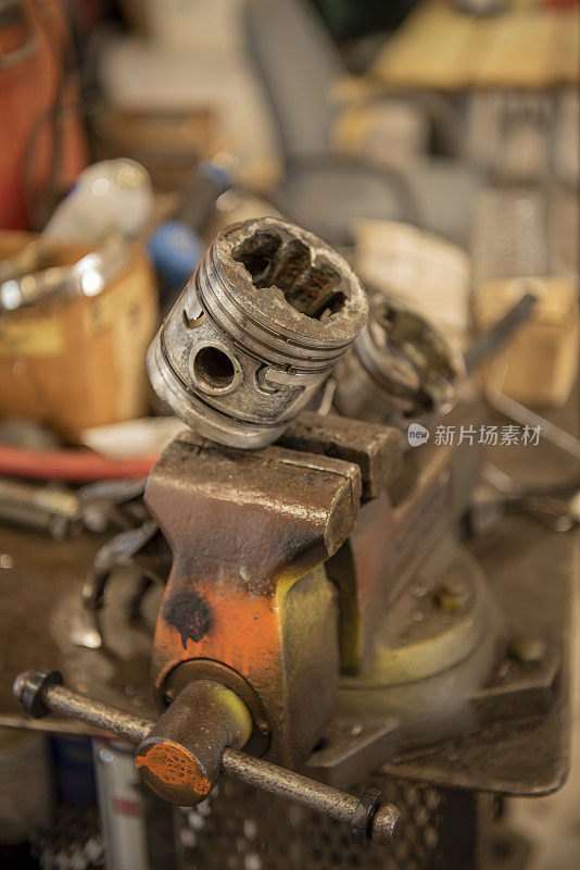 旧的，损坏的活塞连杆，安装在虎钳在机械师的车库里